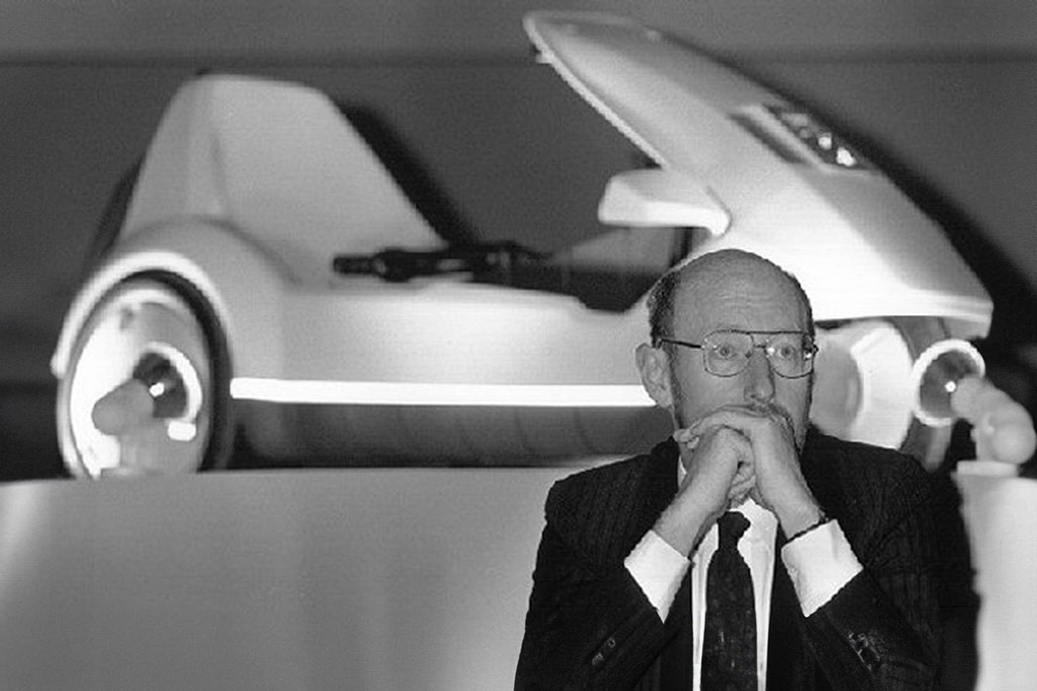A monochrome image of Sinclair looking thoughtful in front of a C5 tricycle