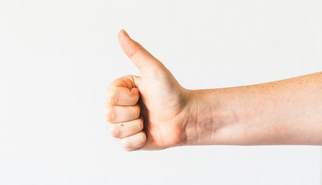 persons right hand doing thumbs up