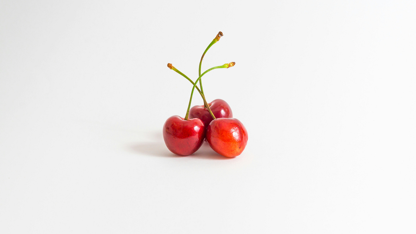 Three cherries on a white background.