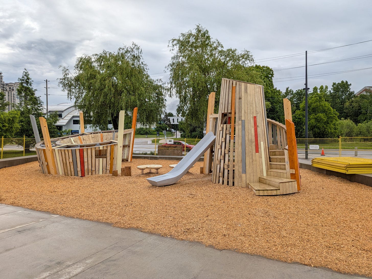 playground at father david bauer drive featuring wooden climbing structures and slide. 