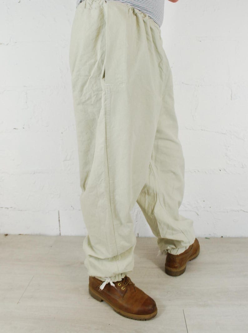 May include: A pair of light beige drawstring pants with a single pocket on the left side.