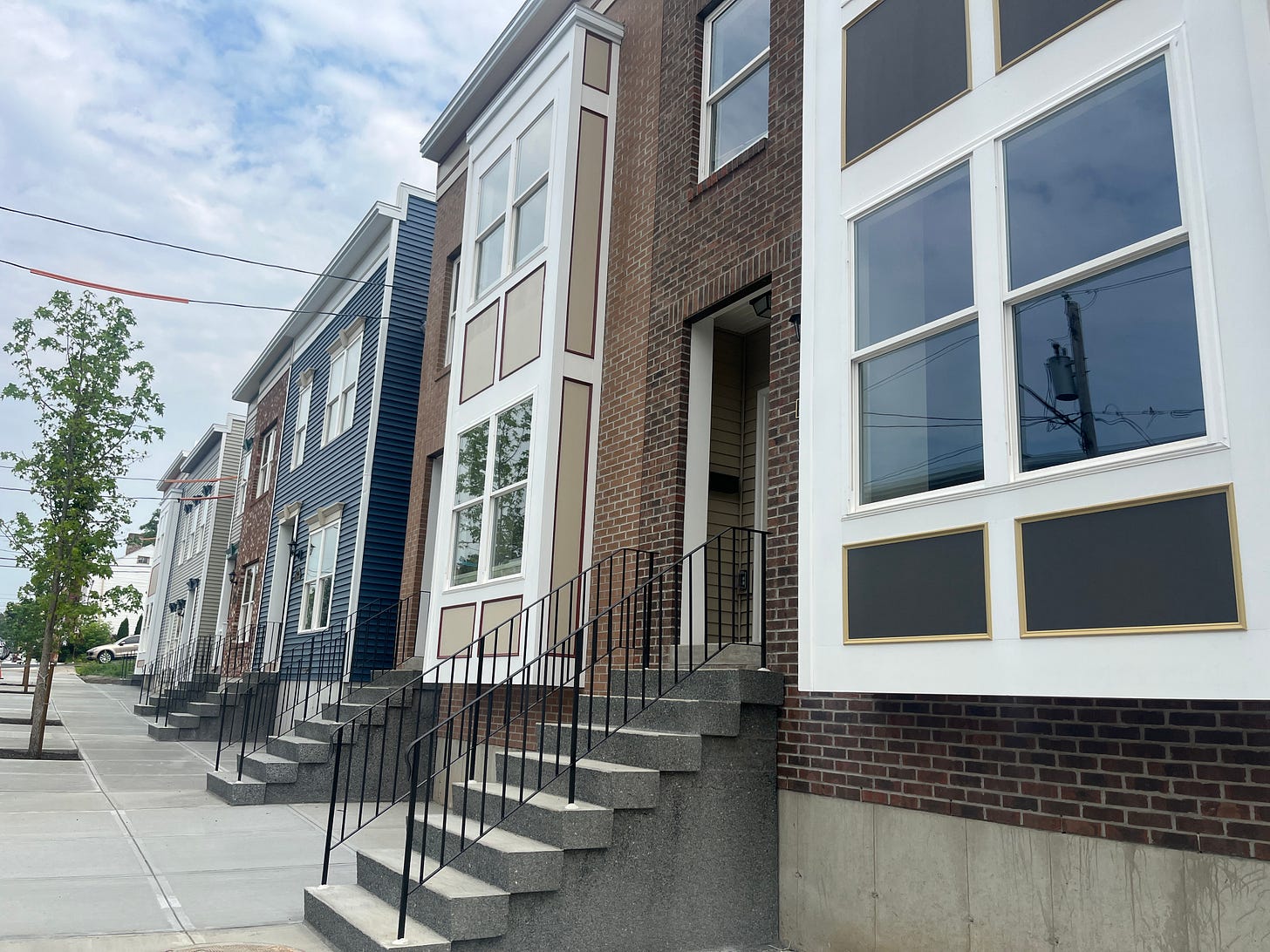 Row of new townhomes, some with brick exteriors and some with colorful siding. 