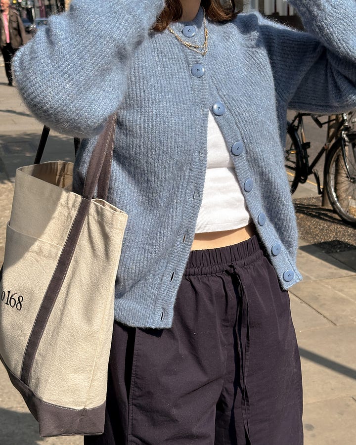 Lucy Moon wears a blue Sezane cardigan, balloon silhouette navy trousers from COS and a Studio 168 tote bag.