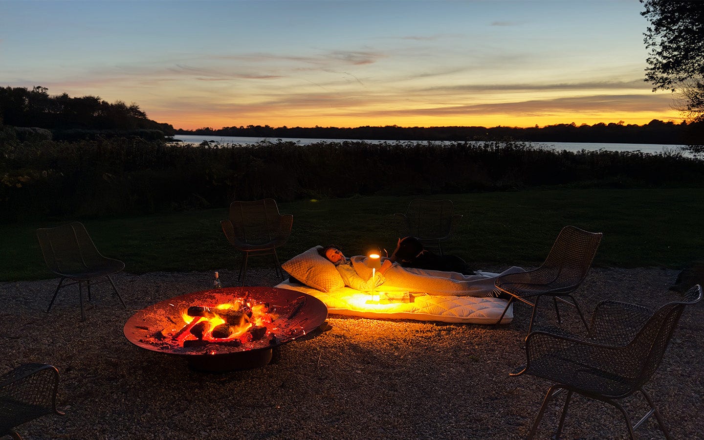 Dr. Catherine lying next to a fire at sunset