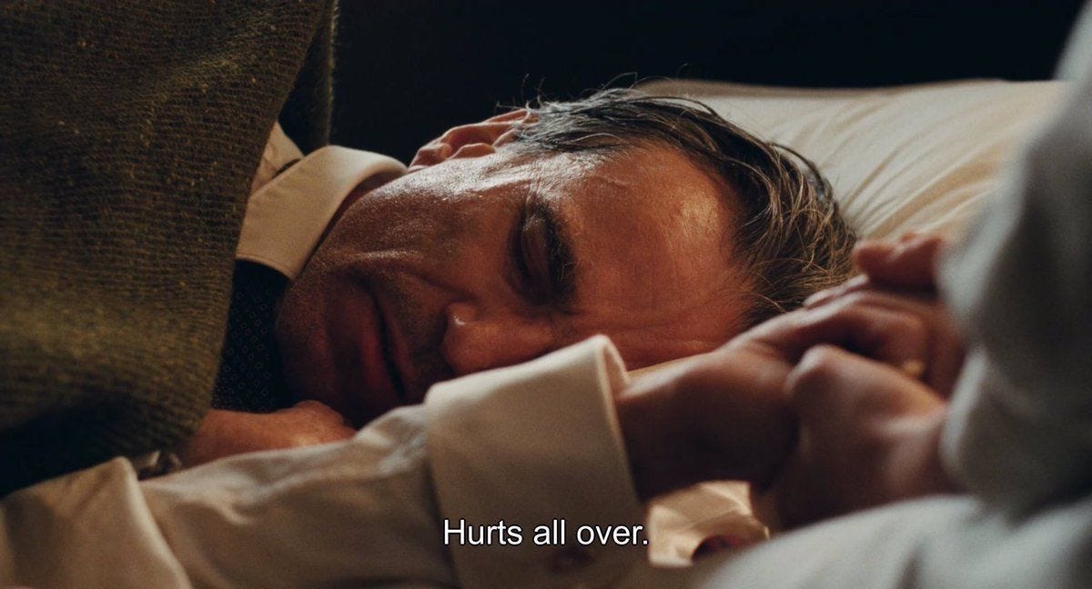 A still from Phantom Thread in which Daniel Day-Lewis is lying in bed. The subtitles read: "Hurts all over."