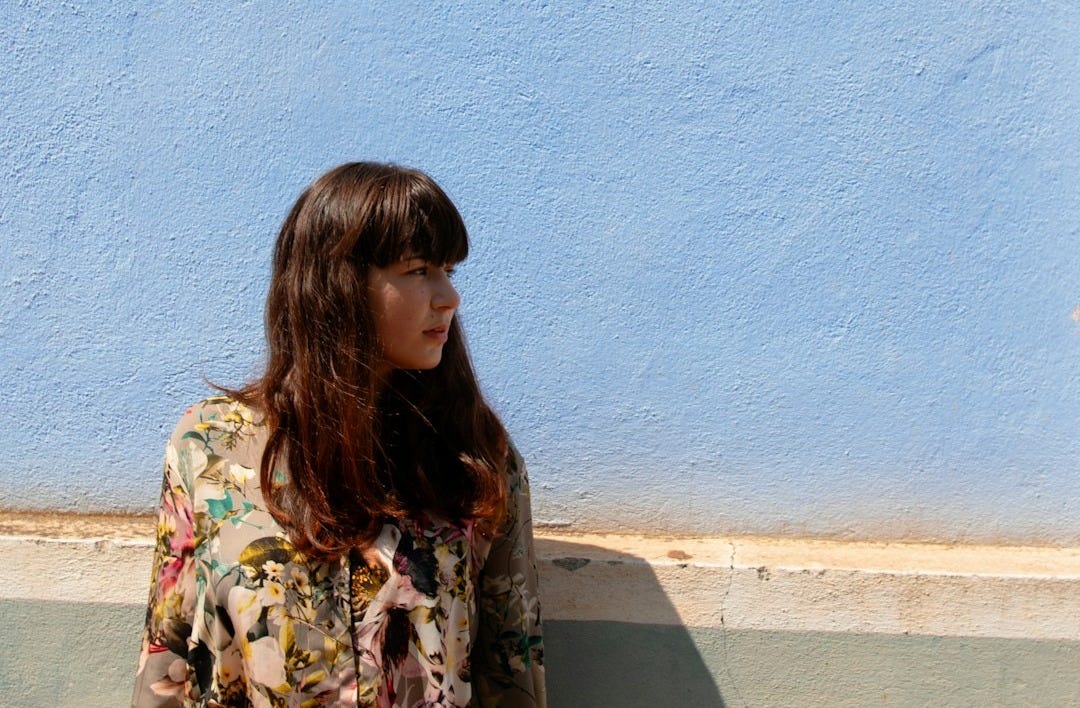 woman standing near blue painted wall and looking on her life