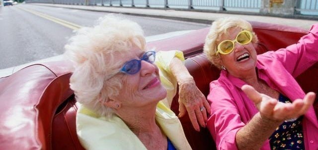This may contain: two older women sitting in the back of a convertible car This may contain: two older women sitting in the back of a convertible car
