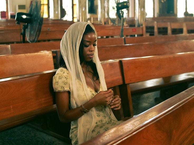 This may contain: a woman sitting in a church looking at her cell phone