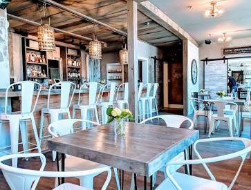 A bright and welcoming event space with tables, chairs, and a bar A bright and welcoming event space with tables, chairs, and a bar