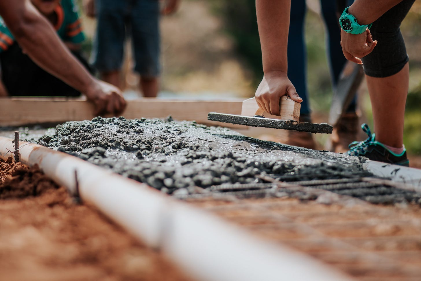 People laying brickwork on top of a heap of cement