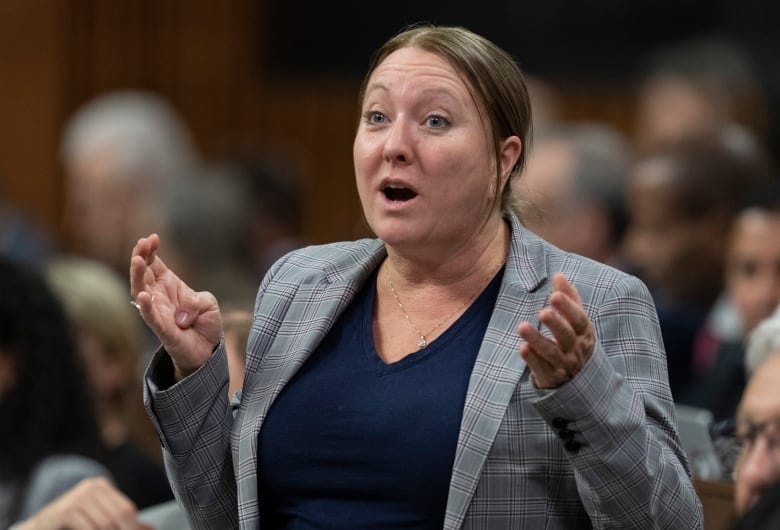 A politician raises her arms while speaking in a legislature. A politician raises her arms while speaking in a legislature.