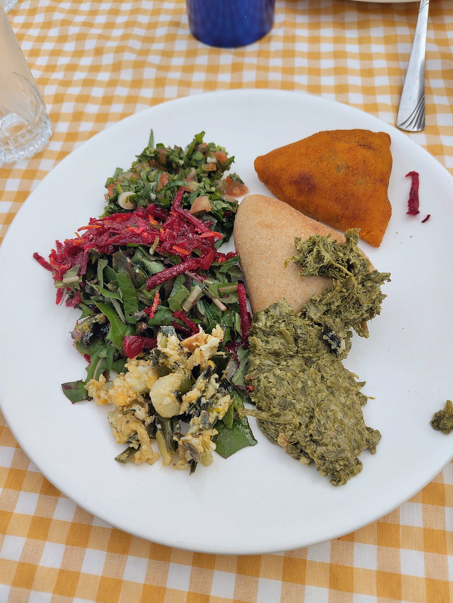 A plate on a picnic table, filled with salads, scrambled eggs, and pastries. A plate on a picnic table, filled with salads, scrambled eggs, and pastries.