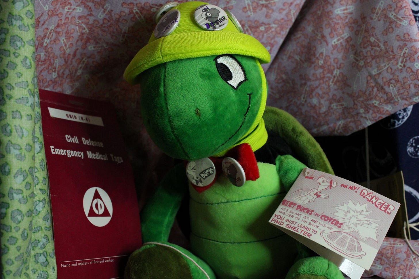 A stuffed Bert the Turtle sits against a pamphlet of Civil Defense Emergency Medical Tags. A stuffed Bert the Turtle sits against a pamphlet of Civil Defense Emergency Medical Tags.