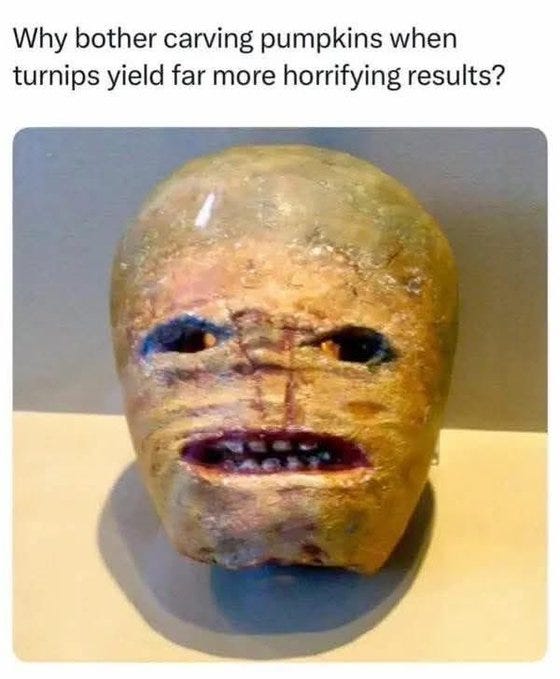 A carved turnip with a horrifying face, showing wide blue eyes, stitched seams across the forehead and cheeks, a grimacing mouth with visible teeth, and rough textured skin in earthy tones, placed on a neutral background.