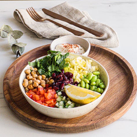 Chickpea-Edamame Salad served in a bowl with fresh spinach, romaine, cucumber, bell pepper, and a creamy hummus dressing.