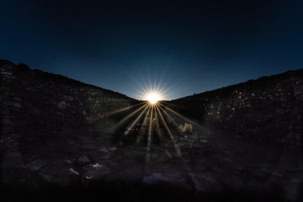 A glinting sun rising over a darkened hillside. A glinting sun rising over a darkened hillside.