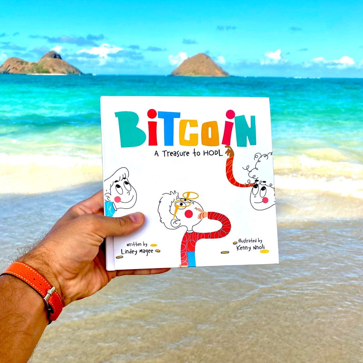 Hand holding a book titled 'Bitcoin: A Treasure to Hold' with a beach in the background Hand holding a book titled 'Bitcoin: A Treasure to Hold' with a beach in the background