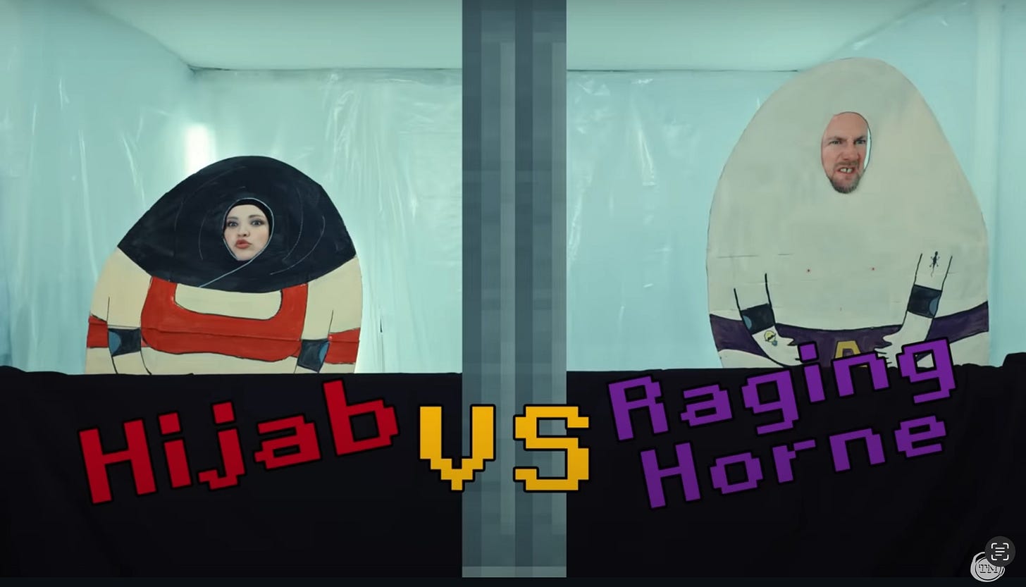 Fatiha El-Ghorri and Little Alex Horne wear hand-painted egg-shaped cardboard cutouts. Text along the bottom reads “Hijab vs. Raging Horne.”