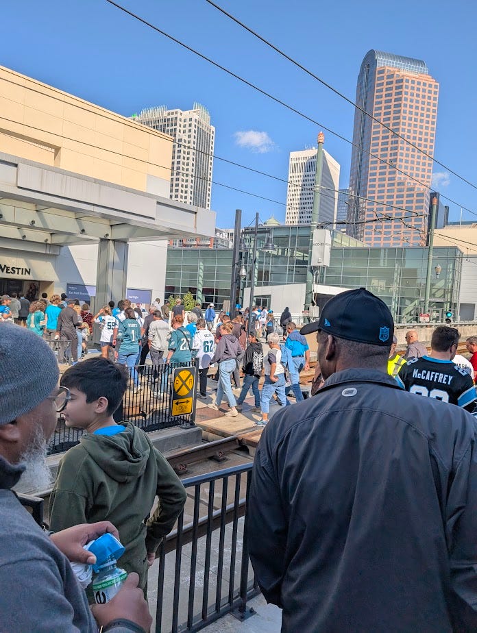 People walking over train tracks at a light rail station in Charlotte, NC