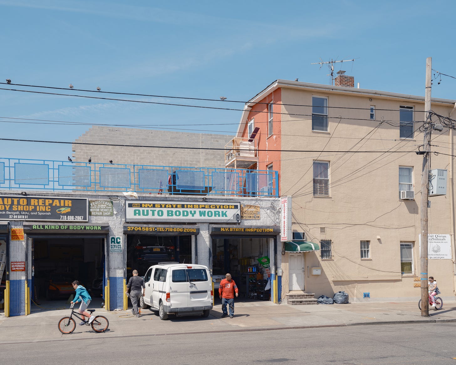 2 kids bike by Auto Body Shop under telephone wires populated by pigeons