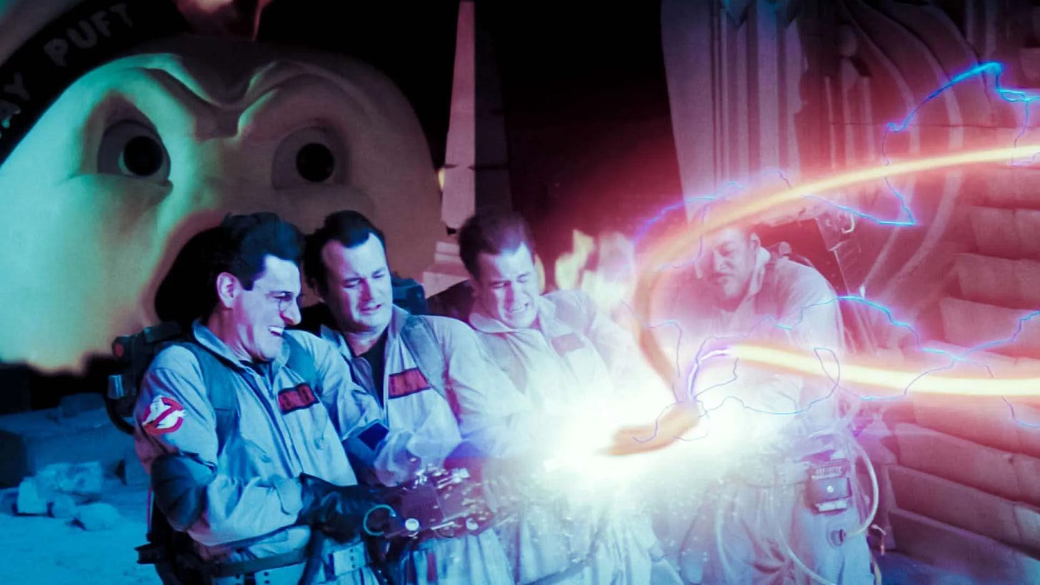 Film still from Ghostbusters showing four ghost-hunting figures in grey jumpsuits crossing bright proton streams in a dramatic blast of blue, pink and white light, used as a playful visual reference for the Dream Eaters interview and the idea of “crossing the streams.” Film still from Ghostbusters showing four ghost-hunting figures in grey jumpsuits crossing bright proton streams in a dramatic blast of blue, pink and white light, used as a playful visual reference for the Dream Eaters interview and the idea of “crossing the streams.”