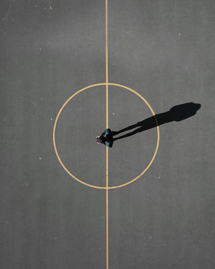 Person standing in a painted circle on blacktop. Solar eclipse. Photos by Luis Eusebio and Mark Tegethof via Unsplash