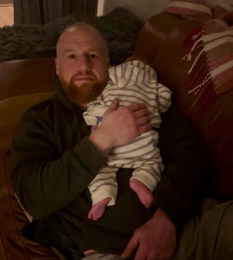 Adam holding his infant son, Marcus.