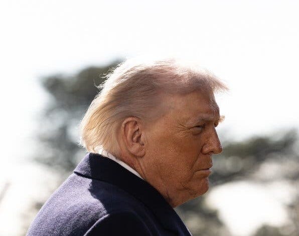 President Trump standing outside wearing a dark coat.