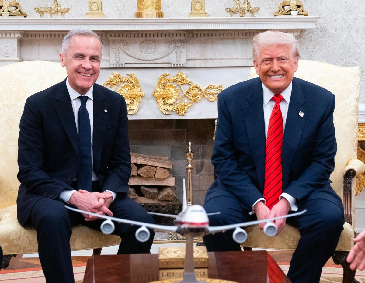 Prime Minister Mark Carney and President Donald Trump smile for a photo while sitting next to each other in the Oval Office, in Washington, D.C.
