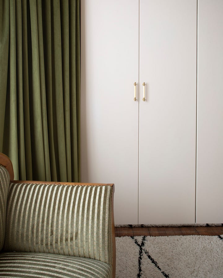 wardrobes, bed with pink curtain above and yellow bedside table with lamp on