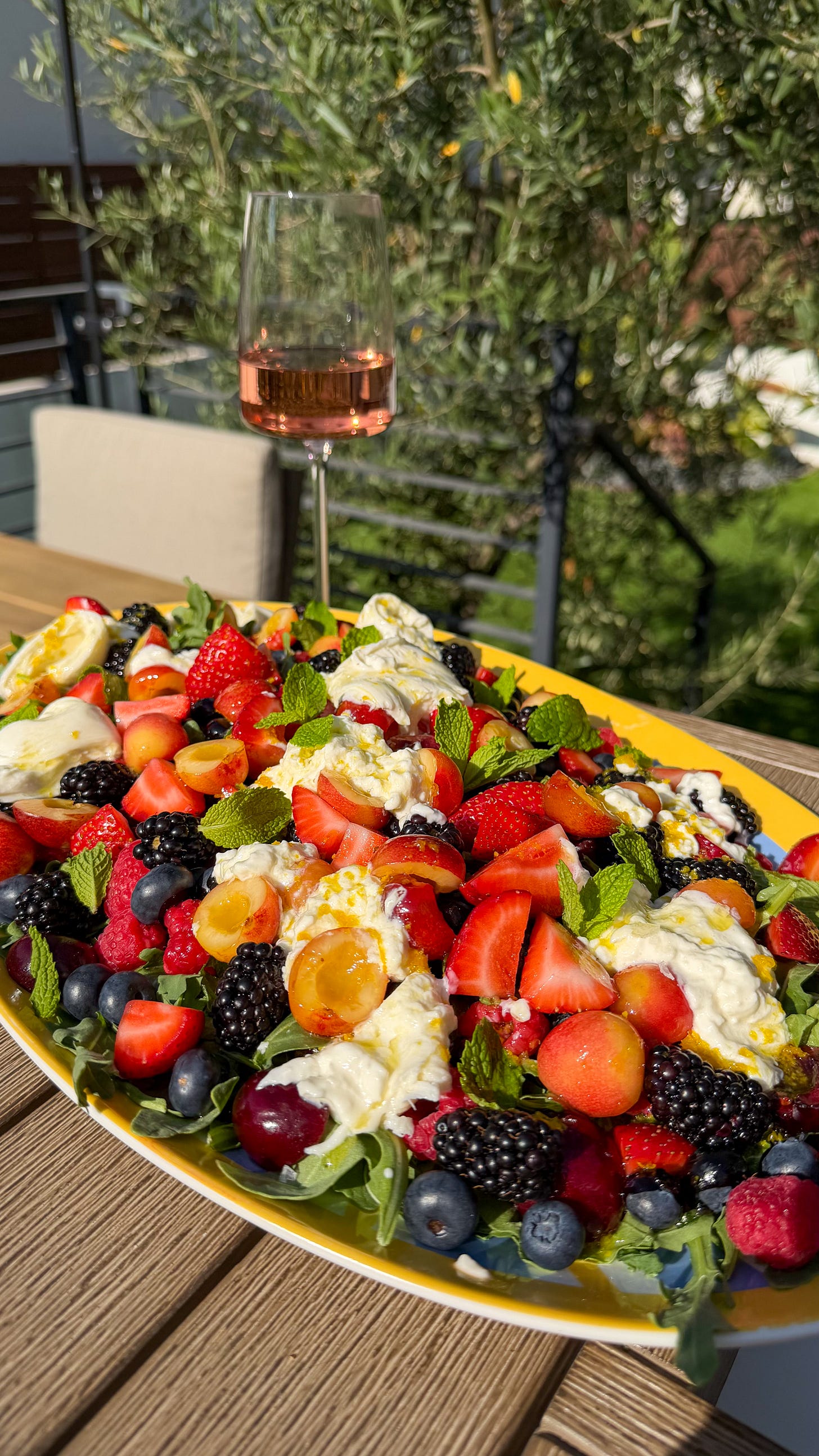 Cherry Berry Burrata Salad with a glass of rosé wine in an al fresco setting.