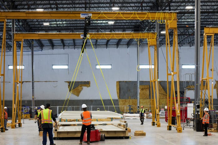 Workers use a large crane to assemble Crusoe Spark units in the Brighton factory. Workers use a large crane to assemble Crusoe Spark units in the Brighton factory.