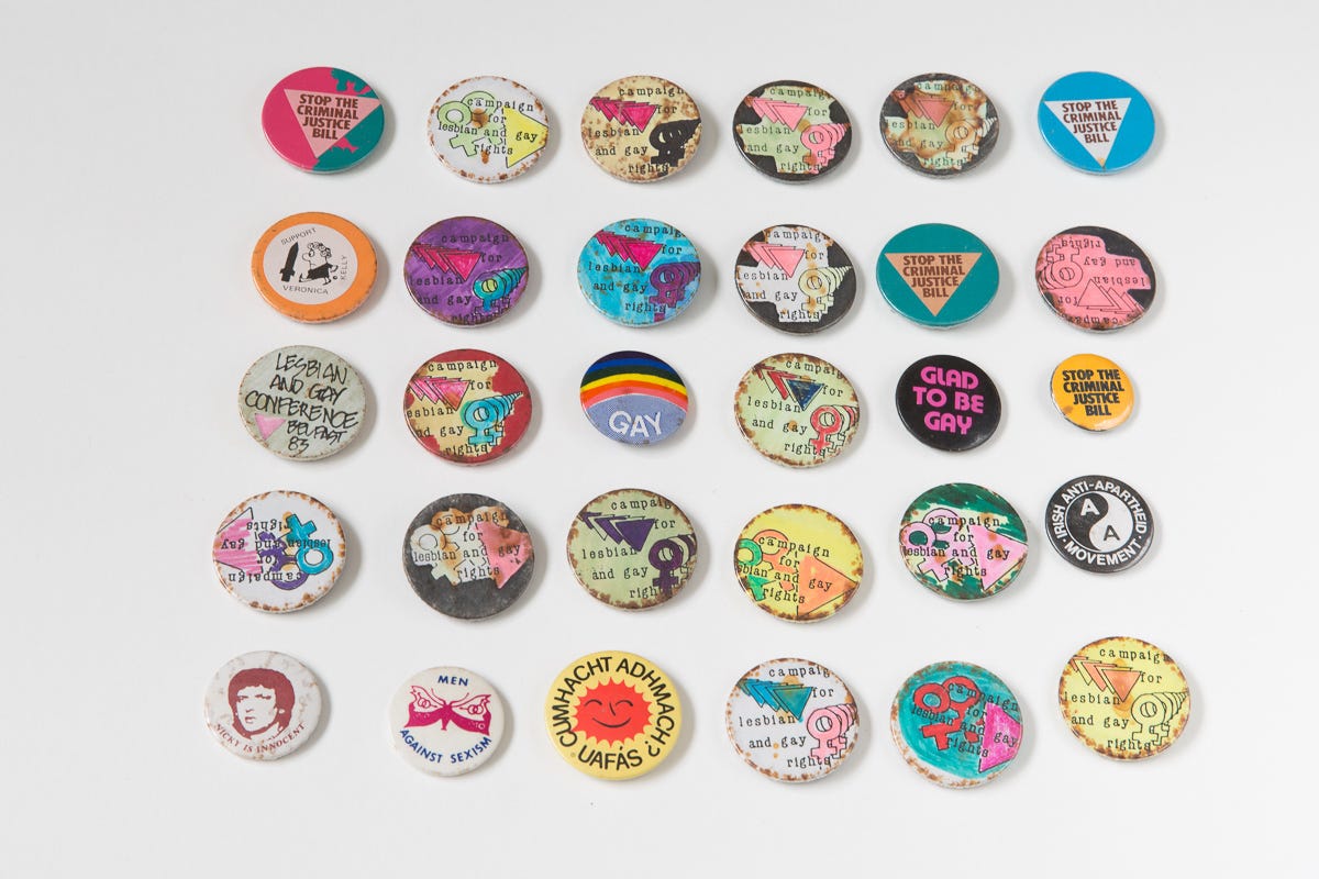  A variety of colorful buttons and badges displayed on a white wall, showcasing different designs and messages.