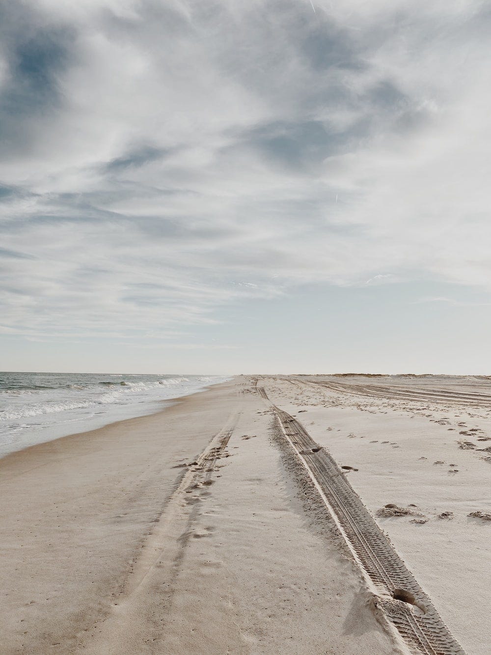 brown sand near sea under white clouds during daytime