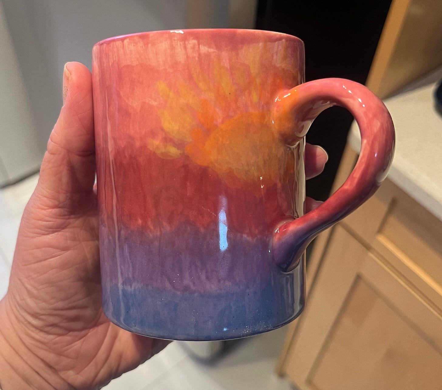 My mug goes from light pink at the top, to darker pink, to light purple, to darkest purple at the base. In the light pink area, there is an orange-and-yellow sunrise. My mug goes from light pink at the top, to darker pink, to light purple, to darkest purple at the base. In the light pink area, there is an orange-and-yellow sunrise.