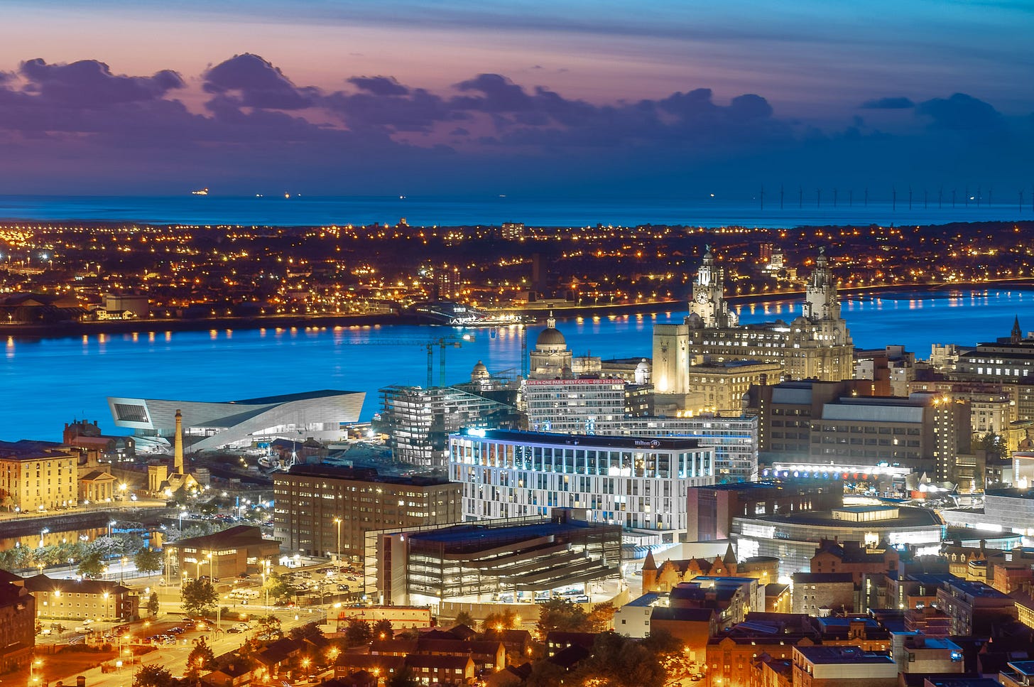 Dusk. The lights of the city are on. This is the Liverpool waterfront from the Museum of Liverpool to the Liver Building.