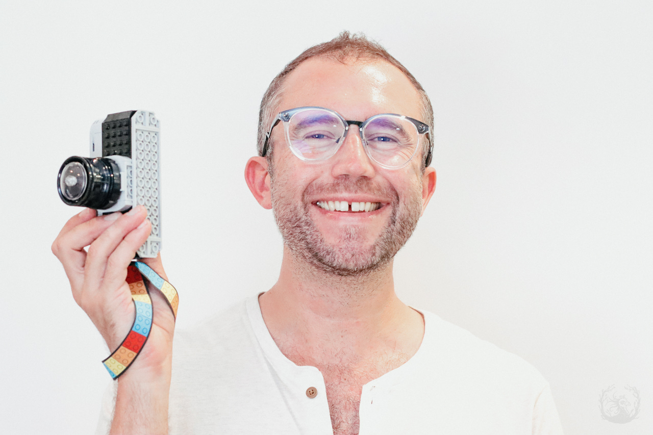 A photograph of the author, Lucas Van Wyk Joel, holding a toy LEGO camera.