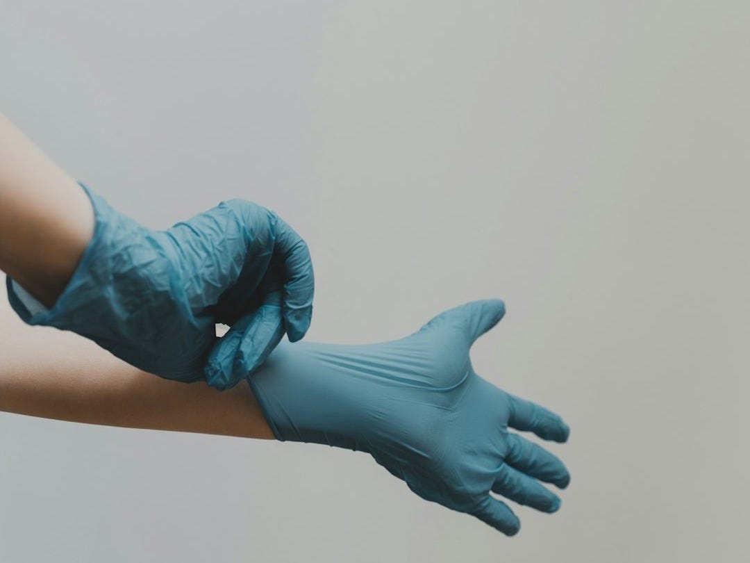 person putting on blue medical gloves person putting on blue medical gloves