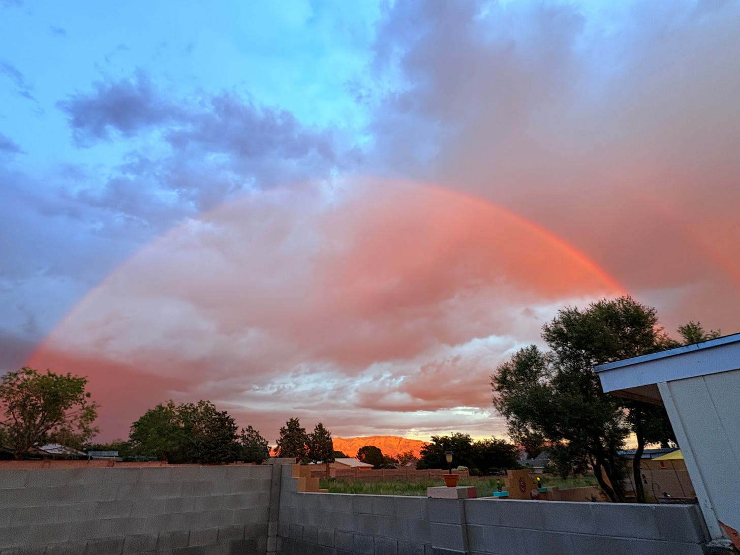 Rainbow over the top of the Sandias glowing pink in the sunset