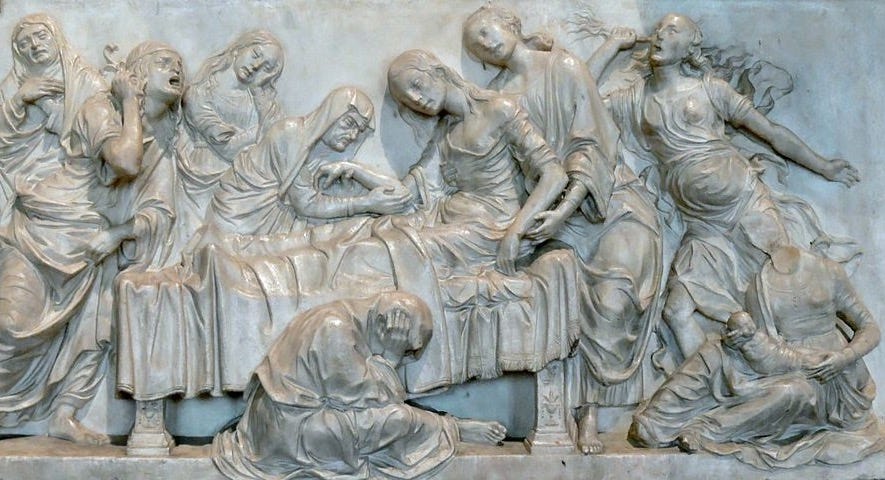 Figure 1-6. A marble relief depicts a women half lying in bed, half being supported by two female attendants. One female attendant holds a baby near the head of the bed, while five other attendants wail in despair around the bed.