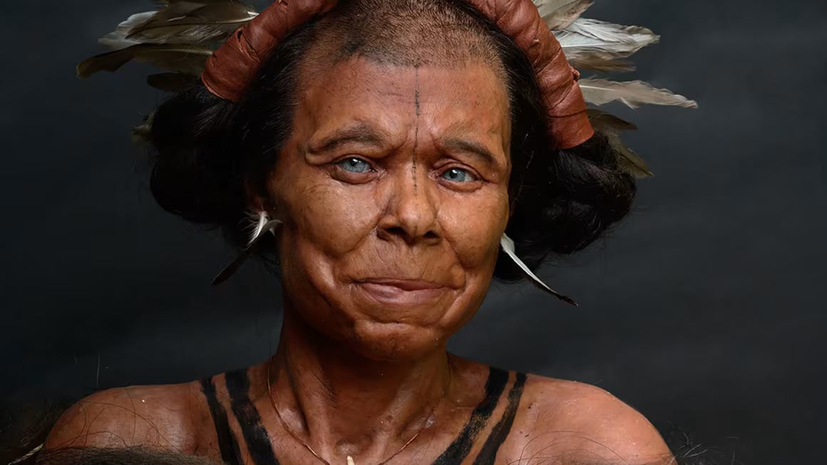 Reconstructed face of prehistoric European woman with feathered headdress, facial tattoos, tanned olive skin, blue eyes and great smile 