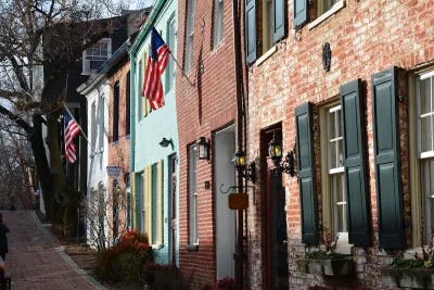 Row of colorful two-story brick residential buildings in Washington, D.C. with U.S. flags hanging from doorways.