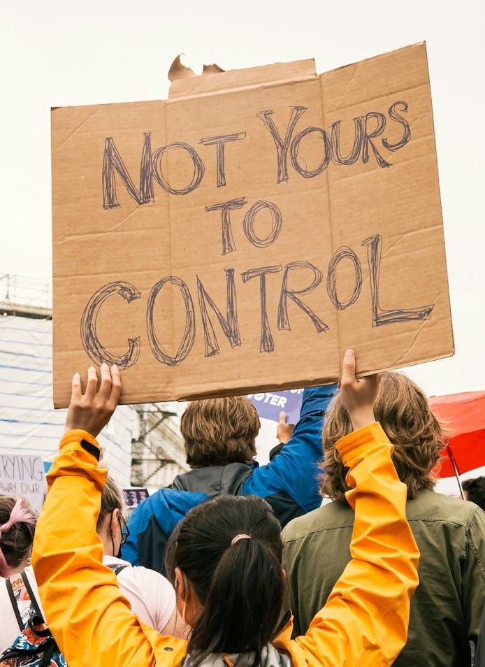 a group of people holding a sign that says not yours to control a group of people holding a sign that says not yours to control