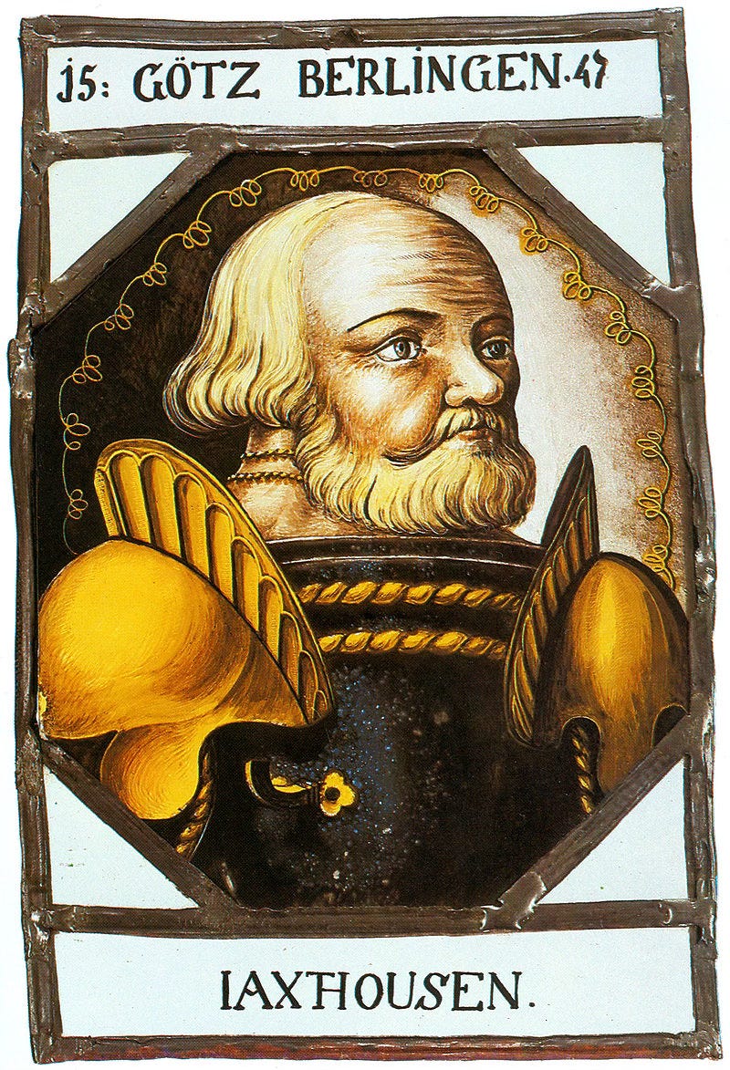 A painting of ​​Götz wearing his armor. He has a receding hairline with long blond locks and a full beard. The accompanying text explains that he was born in the municipality of Jagsthausen, and that the portrait was made in 1547, when he would’ve been 67 years old.