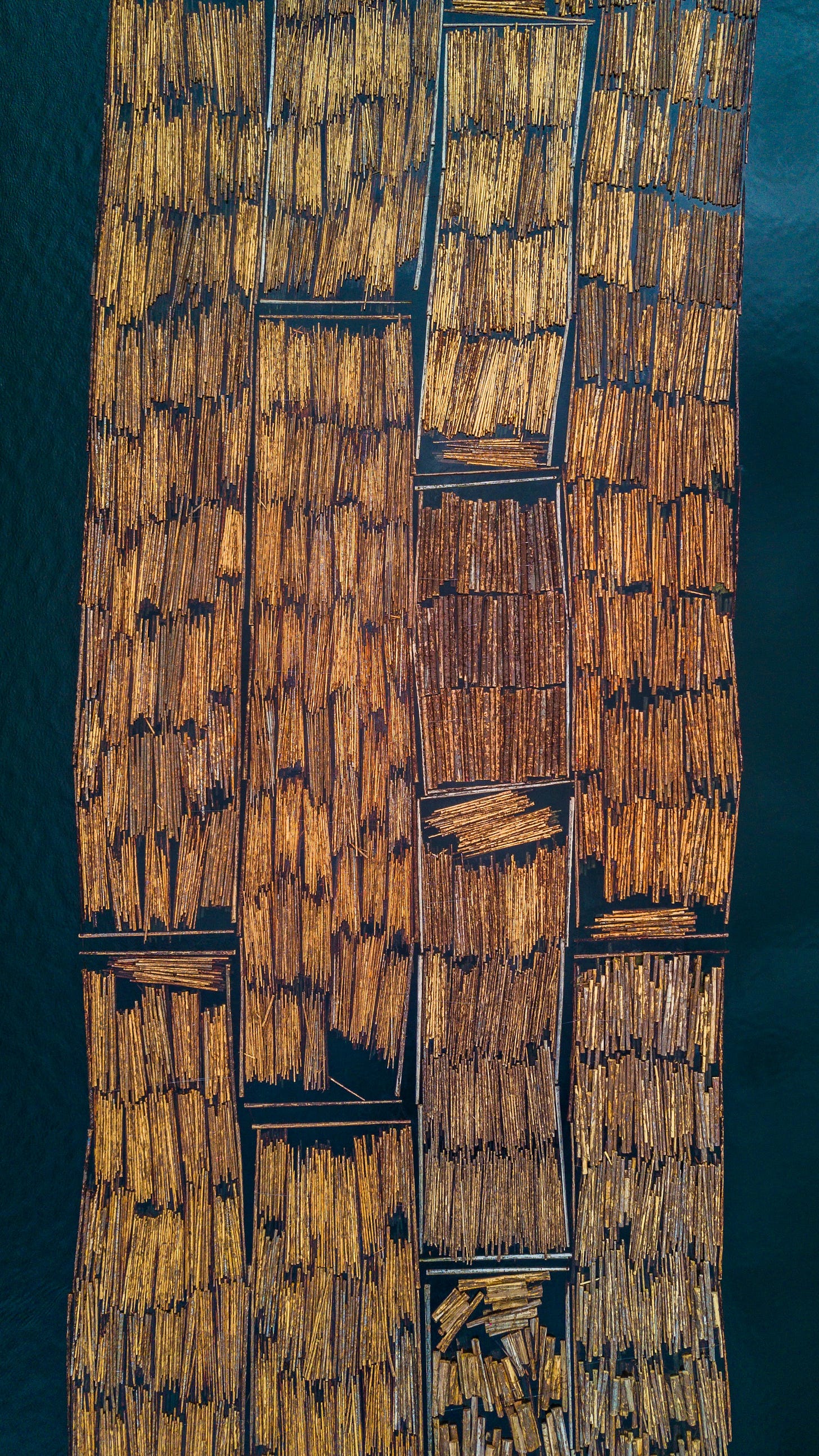 An aerial view of a raft made of logs on water. There are gaps in between the logs and it isn't well-suited for carrying passengers. An aerial view of a raft made of logs on water. There are gaps in between the logs and it isn't well-suited for carrying passengers.