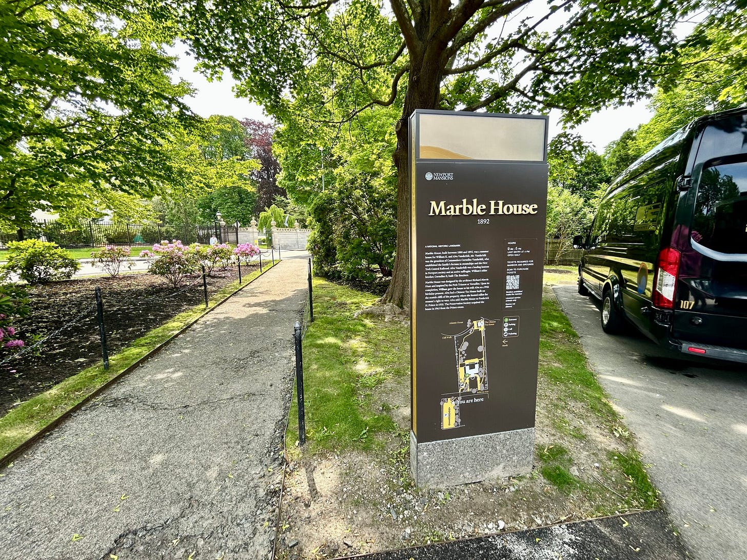 sign, sidewalk, fence, trees, cars