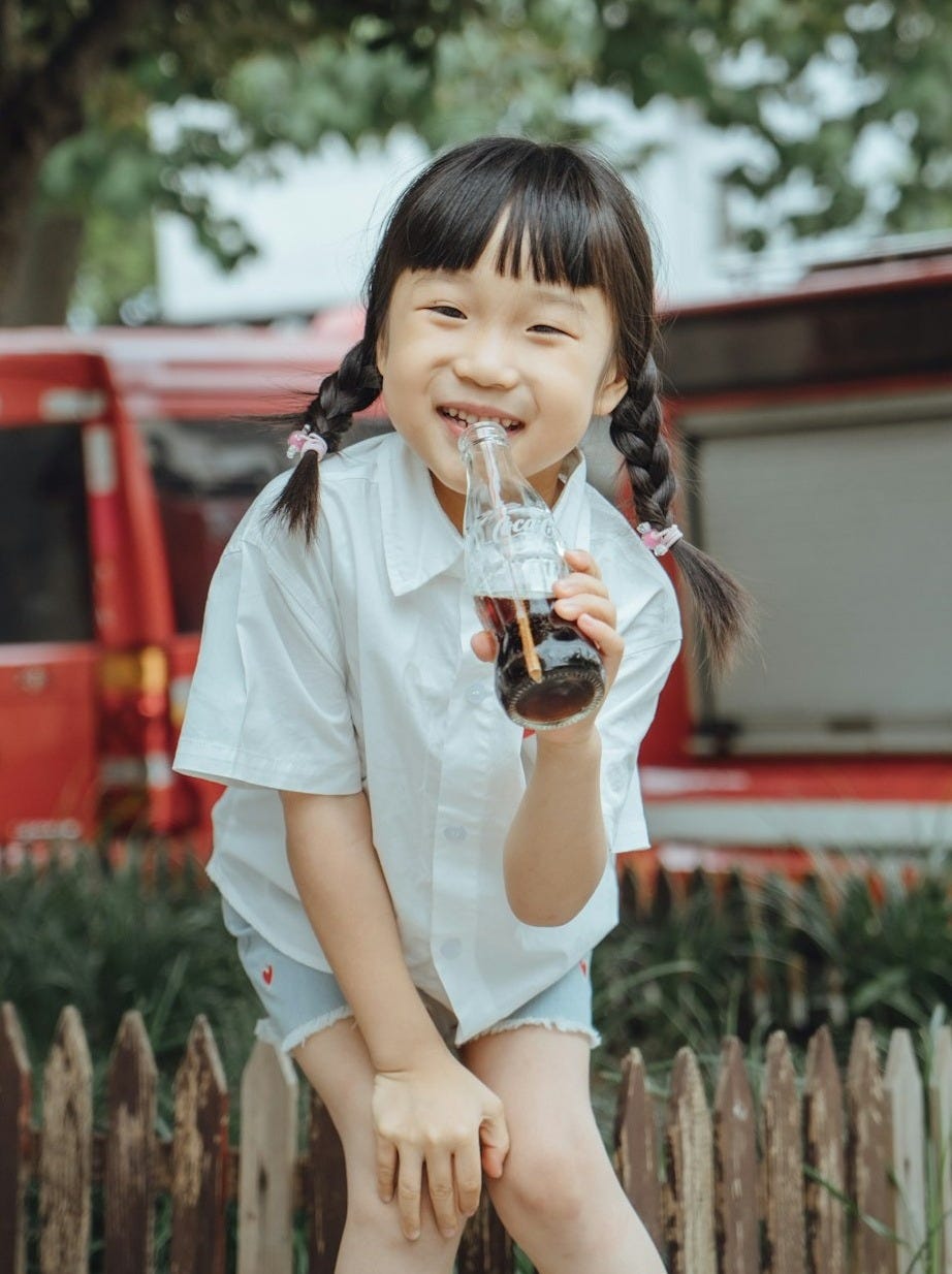 a little girl holding a glass of wine