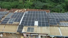Four buildings with rusty roofs and dozens of solar panels mounted on top Four buildings with rusty roofs and dozens of solar panels mounted on top