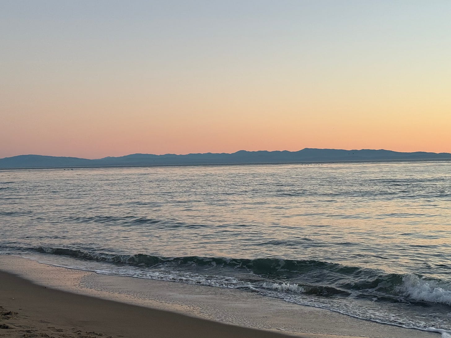 sunset with mountain horizon over ocean