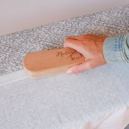 using a clapper on a hem of a white curtain